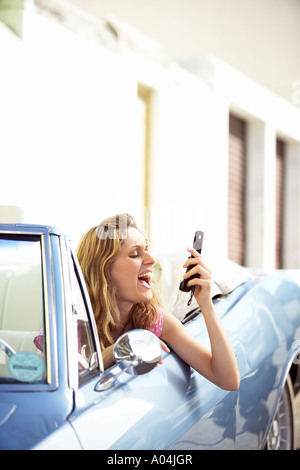 Mädchen im Cabrio Blick auf Nachricht auf dem Handy Stockfoto