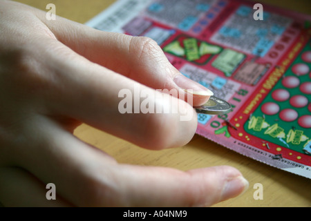 Kratzen Sie ein BINGO-Spiel mit einem Loonie von einer weiblichen hand Stockfoto