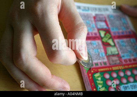 Kratzen Sie ein BINGO-Spiel mit einem Loonie von einer weiblichen hand Stockfoto