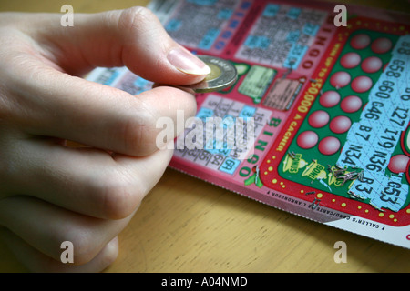 Kratzen Sie ein BINGO-Spiel mit einem Loonie von einer weiblichen hand Stockfoto