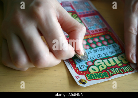 Kratzen Sie ein BINGO-Spiel mit einem Loonie von einer weiblichen hand Stockfoto