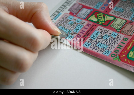 Kratzen Sie ein BINGO-Spiel mit einem Loonie von einer weiblichen hand Stockfoto