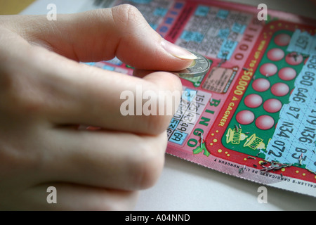 Kratzen Sie ein BINGO-Spiel mit einem Loonie von einer weiblichen hand Stockfoto