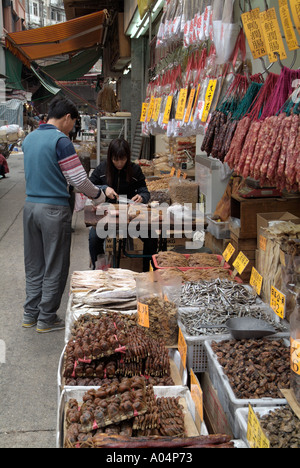 dh des Voeux Road West SHEUNG WAN HONG KONG Girl Schneiden von Fleisch Trocknen Street Stall Shop chinesisch konserviert getrocknetes Fleisch asiatischer Anbieter außerhalb des Marktes Stockfoto