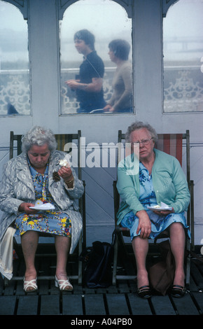 Senioren Rentner essen Sticky Buns Palace Pier von Brighton East Sussex England 1980 s, im 80s HOMER SYKES Stockfoto