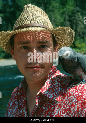 Ein Mann unter seinem Papagei afrikanische Grau draußen auf seiner Schulter außerhalb. Stockfoto