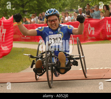 Ein Mann im Rollstuhl feiert nach dem Sieg der Rollstuhl Division eines Marathons. Stockfoto