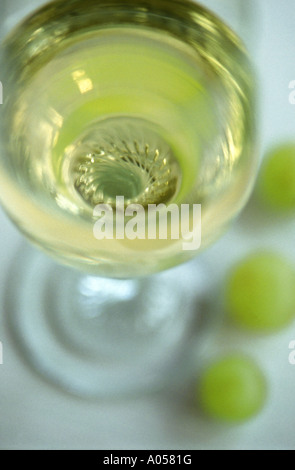 Abstrakte Schuss Blick in ein Glas Weißwein mit drei Trauben an der Basis Stockfoto