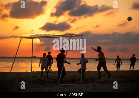 Silhouette von einer Gruppe von Männern laufen und spielen Fußball am Strand bei Sonnenuntergang Isla Mujeres Mexiko Stockfoto