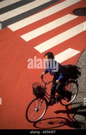 Draufsicht auf eine Frau, die mit dem Fahrrad auf einer Stadt Straße in Tokio Japan Stockfoto