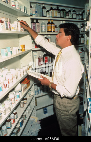 Eine männliche Phatmacist nehmen eine Inventur der verschiedenen Arzneimittel auf dem Regal Stockfoto