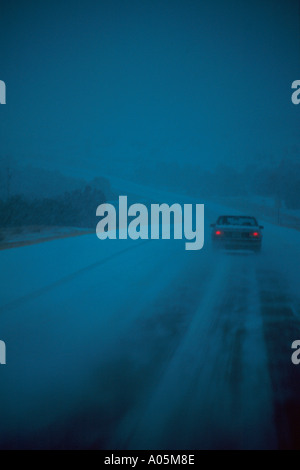 Ein einsames Auto auf einer einsamen Straße während eines Schneesturms Winter in der Nähe von Trinity Colorado USA vertikal Stockfoto