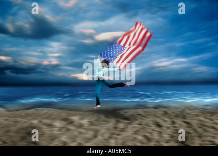 Frau, die entlang des Strandes unter der Flagge des U im wind Stockfoto