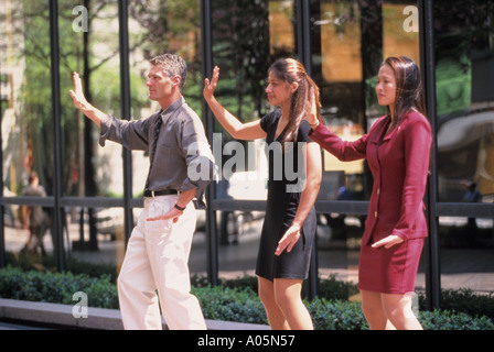 Ein Mann und zwei Frauen aus unterschiedlichen Ethnizität Praxis Tai Chi Kampfkunst im Freien während während ihrer Mittagspause brechen von der Arbeit Stockfoto