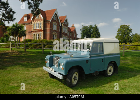 Sehr originelle 1977ish Landrover Serie 3 Hardtop auf Feld mit großen Landhaus im Hintergrund. Stockfoto