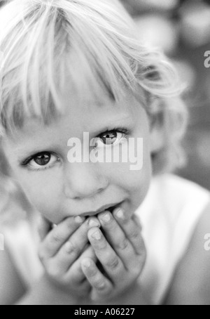 Gesicht-Porträt der jungen Mädchen 5,6,7 alten Blick in die Kamera mit unschuldigen großen süßen traurigen Augen und Hände an Lippen Mund Nahaufnahme Stockfoto