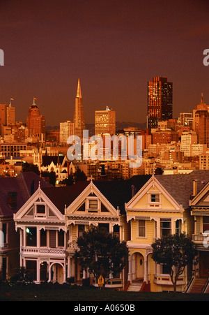 Viktorianische Häuser auf Steiner Street Alamo Square bei Sonnenuntergang mit Skyline über San Francisco Kalifornien, USA Stockfoto