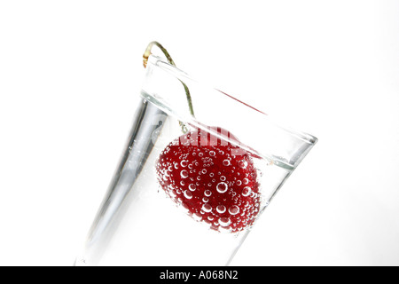 Eine Kirsche eintauchen in ein Glas Wasser Stockfoto