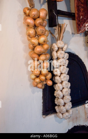 Traditionelle Kücheneinrichtung aus Krakau Polen mit hängenden Zwiebeln und Knoblauchzwiebeln an einer rustikalen weißen Wand. Stockfoto