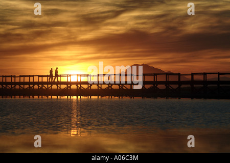 Paare, die auf einer Brücke bei Sonnenuntergang Stockfoto