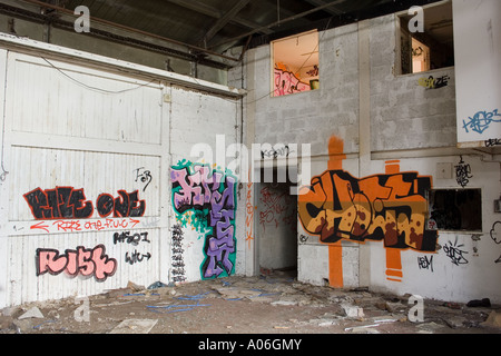 Graffiti Wandmalereien spritzlackiert überall auf den Wänden in einem verlassenen Lagerhaus in Dundee, Großbritannien Stockfoto