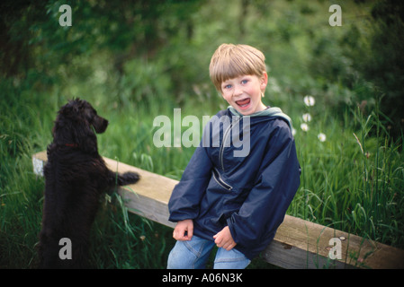 Sechs Jahre alter Junge mit schwarzen Cocker Spaniel Welpen auf Spaziergang in das Land Norfolk UK Stockfoto