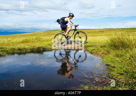 Weibliche Mountainbiker spiegelt sich im Pool auf Crosby Ravensworth fiel in Cumbria mit der Pennines auf die skyline Stockfoto