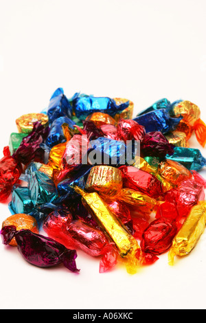 Saisonale festliche bunte Pralinen Süßigkeiten Bonbons mit glänzenden Folie Wrapper in einem Stapel auf weißem Hintergrund Stockfoto