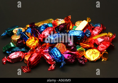 Nahaufnahme Detail sortierten gefärbt hell Schokolade Süßigkeiten Candy Folie Wrapper zufälliger Haufen Süßwaren schwarzer Hintergrund Stockfoto
