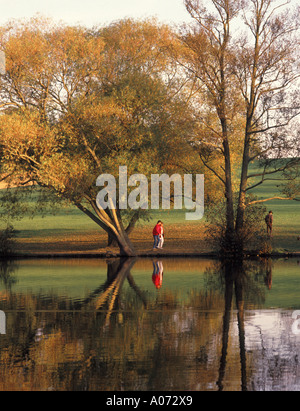 Brentwood Essex Weald Country Park See mit Reflexionen von Baum Herbstfärbung und Wanderer Stockfoto