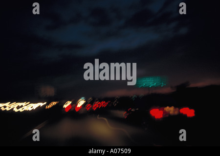 Autos-Autos im Verkehr in der Nacht mit farbigen Heck leuchten Scheinwerfer mit bewölktem Himmel Stockfoto