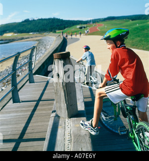 Radfahrer mit grünem Helm auf dem Wales Coast Path Millennium Coastal Park in der Nähe von Llanelli Carmarthenshire Wales UK KATHY DEWITT Stockfoto