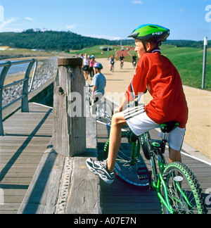 Ein Teenager Radfahrer mit Helm sitzt auf seinem Fahrrad mit Blick auf die Millennium Coastal Park weg inCarmarthenshire Wales UK KATHY DEWITT zu Stockfoto