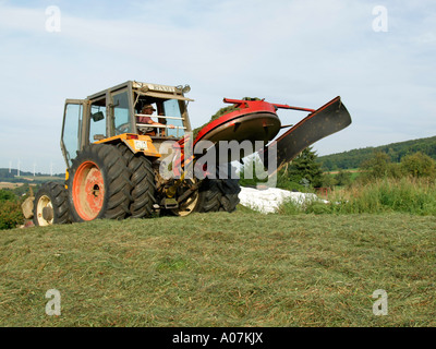 Herstellung von Silage verdichten das Gras Heu mit einem Traktor in einem Feld silo Stockfoto