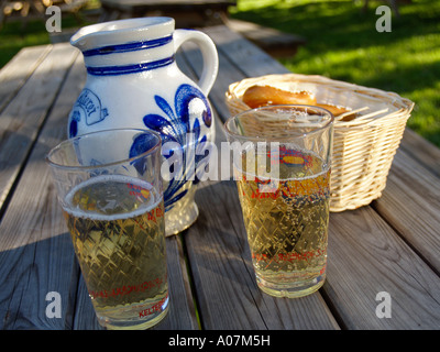 Apfelwein traditionelle Apfel Wein aus Hessen Deutschland in traditionellen typisch gerippten Glas und Keramik Krug mit einer Brezel Stockfoto
