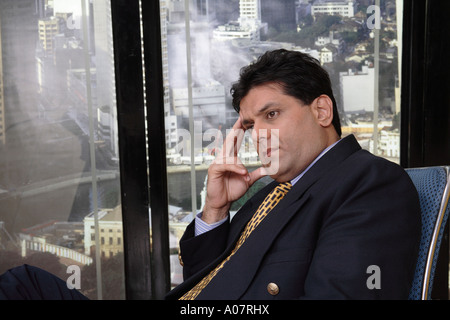 CEO denken, sitzen in seiner Hütte im Business-Anzug mit Stadt-Hintergrund Stockfoto