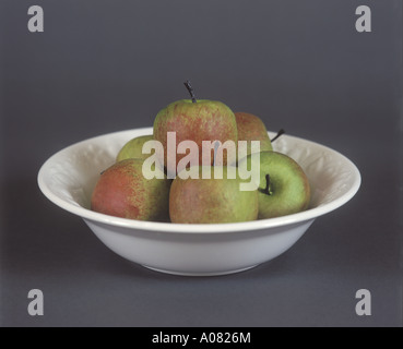 Ernte der Äpfel in eine einfache weiße Obstschale auf einem dunklen Hintergrund Stockfoto