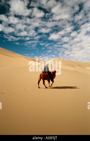 Nomade auf seinem baktrischen Kamel reiten über die Sanddünen von Khongoryn Els in der Gobi Wüste in der äußeren Mongolei. Stockfoto