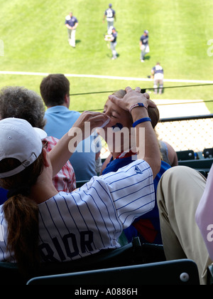 Mutter gilt Bemalung auf ihre Tochter, während sie warten, Baseball-Spiel im Wrigley Field in Chicago starten Stockfoto