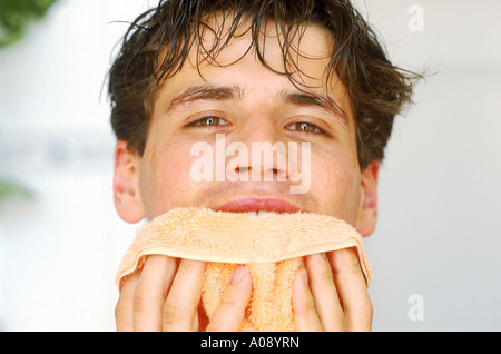 Junger Mann sein Gesicht mit einem Handtuch abwischen Stockfoto