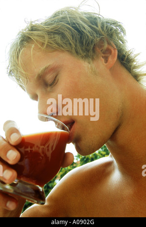 Junger Mann trinken aus einem Glas Stockfoto