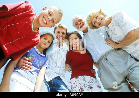 Niedrigen Winkel Ansicht einer Familie mit Arme umeinander blickte lächelnd Stockfoto