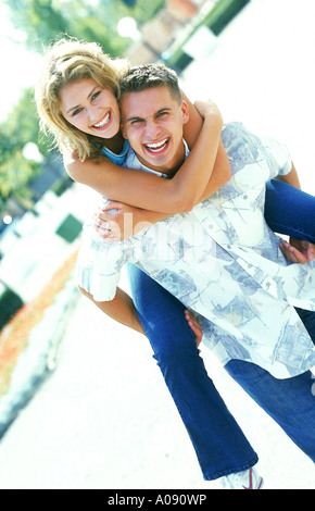 Junge Frau Reiten Huckepack auf einem jungen Mann Stockfoto