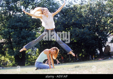 Eine Frau, die einen Sprung über einen anderen hocken auf dem Boden Stockfoto
