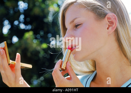 Junge Frau Auftragen von Lippenstift Stockfoto