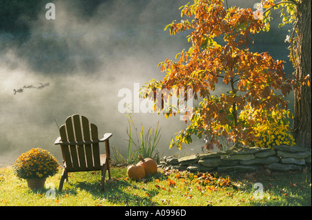 Goldenes Licht: ein Adirondack Stuhl im Spätherbst Nachmittag am See mit Nebel steigt und Orange - allein mit den Enten, Midwest USA Stockfoto