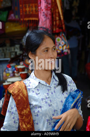 Ziemlich dunkel behaarte balinesische Frau verkaufen Sarongs, Stadtmarkt Ubud, Bali-Indonesien Stockfoto