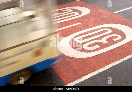 EIN BUS-PÄSSE, DIE MEHR ALS DREIßIG MEILEN PRO STUNDE WARNUNGEN AUF DER STRAßE UK GEMALT BESCHLEUNIGEN Stockfoto