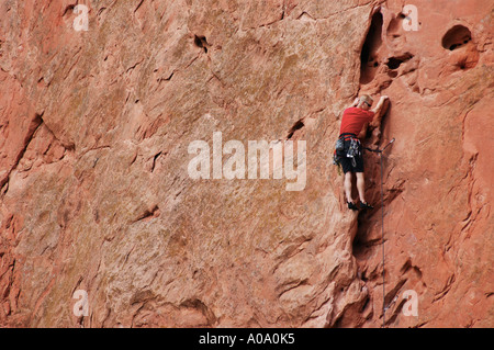 Ein einsamer Kletterer steigt eine riesige rote Felsformation in Colorado. Stockfoto