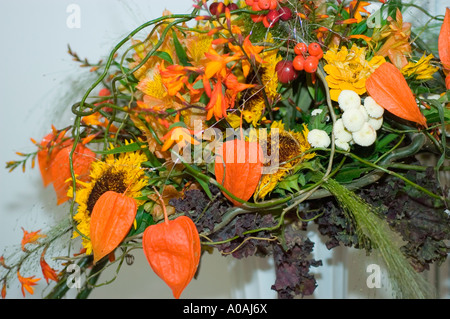 Farbenfrohe Anordnung von gelben und roten Blumen mit Sonnenblumen, chinesischen Laternen, weißen Chrysanthemen und roten Beeren in einem Herbststrauß. Stockfoto